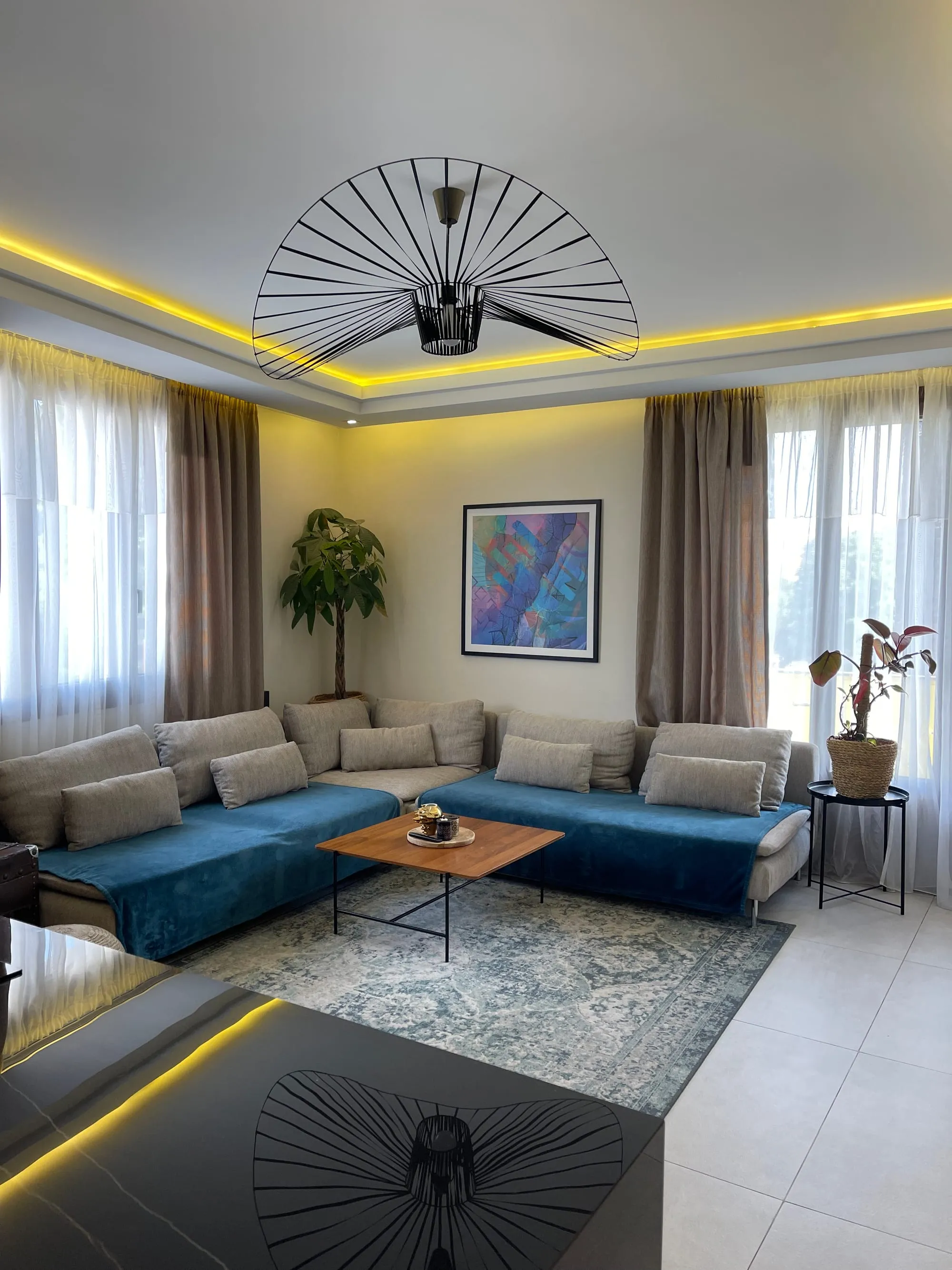 Séjour avec faux plafond à éclairage périphérique, canapé d'angle et fenêtres voilées