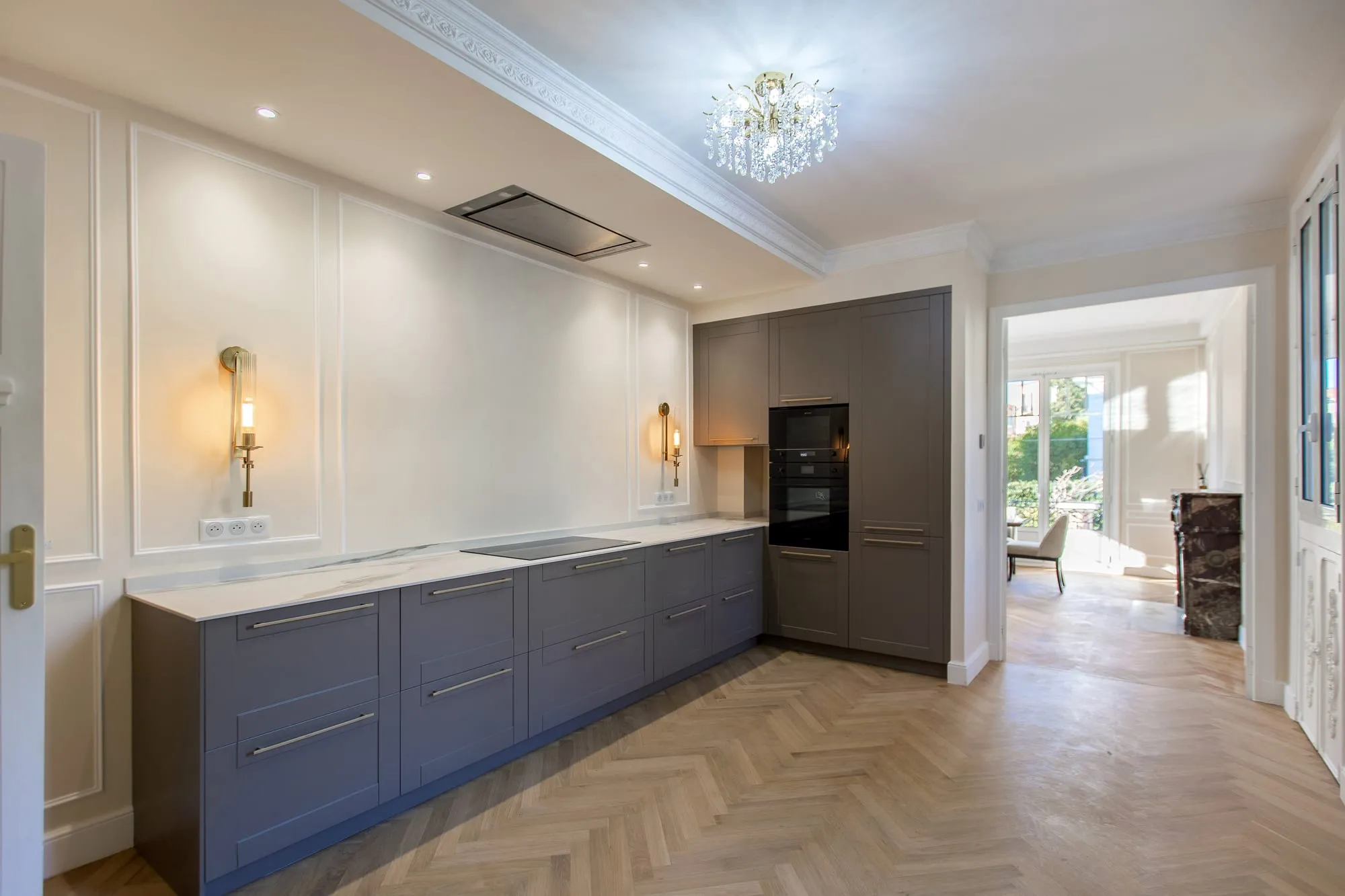 Cuisine équipée gris-bleu avec moulures, ouverte sur l'enfilade des pièces