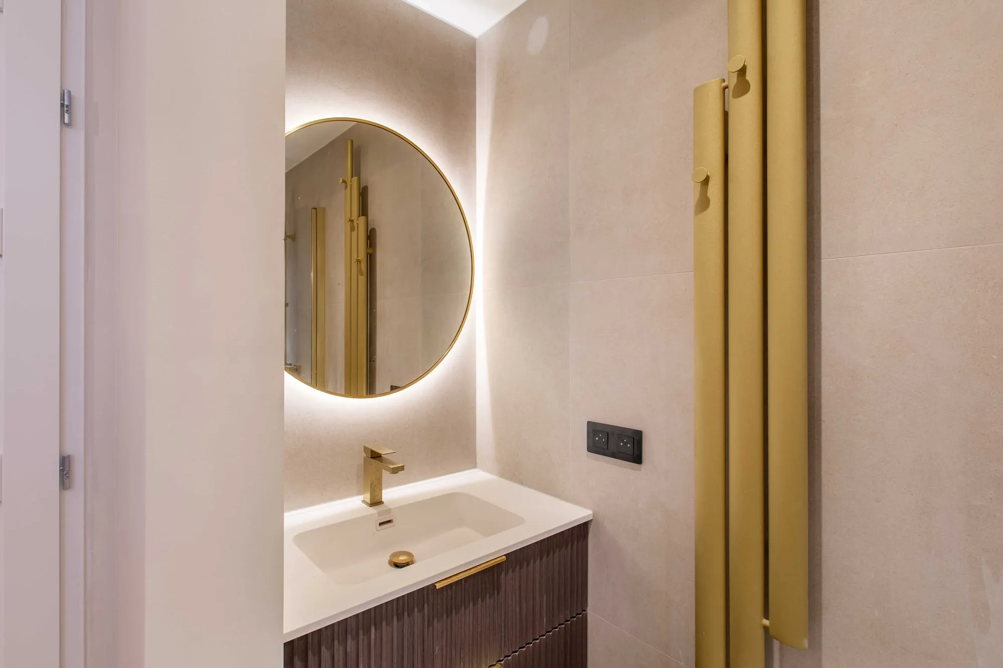 Salle d'eau, vasque suspendue, miroir rond rétroéclairé et robinetterie dorée