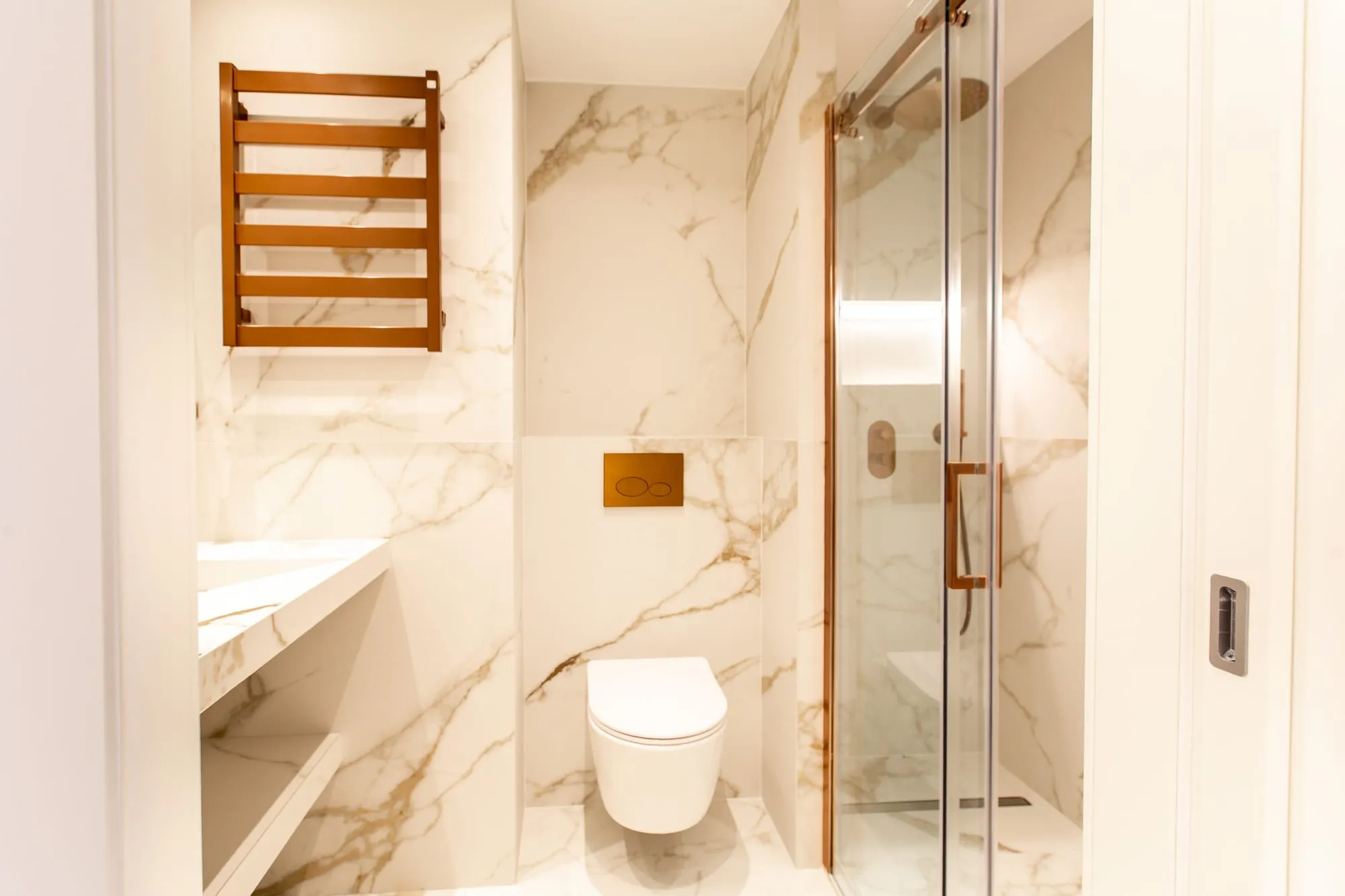 Salle de bains en marbre veiné, douche vitrée et sèche-serviettes bois