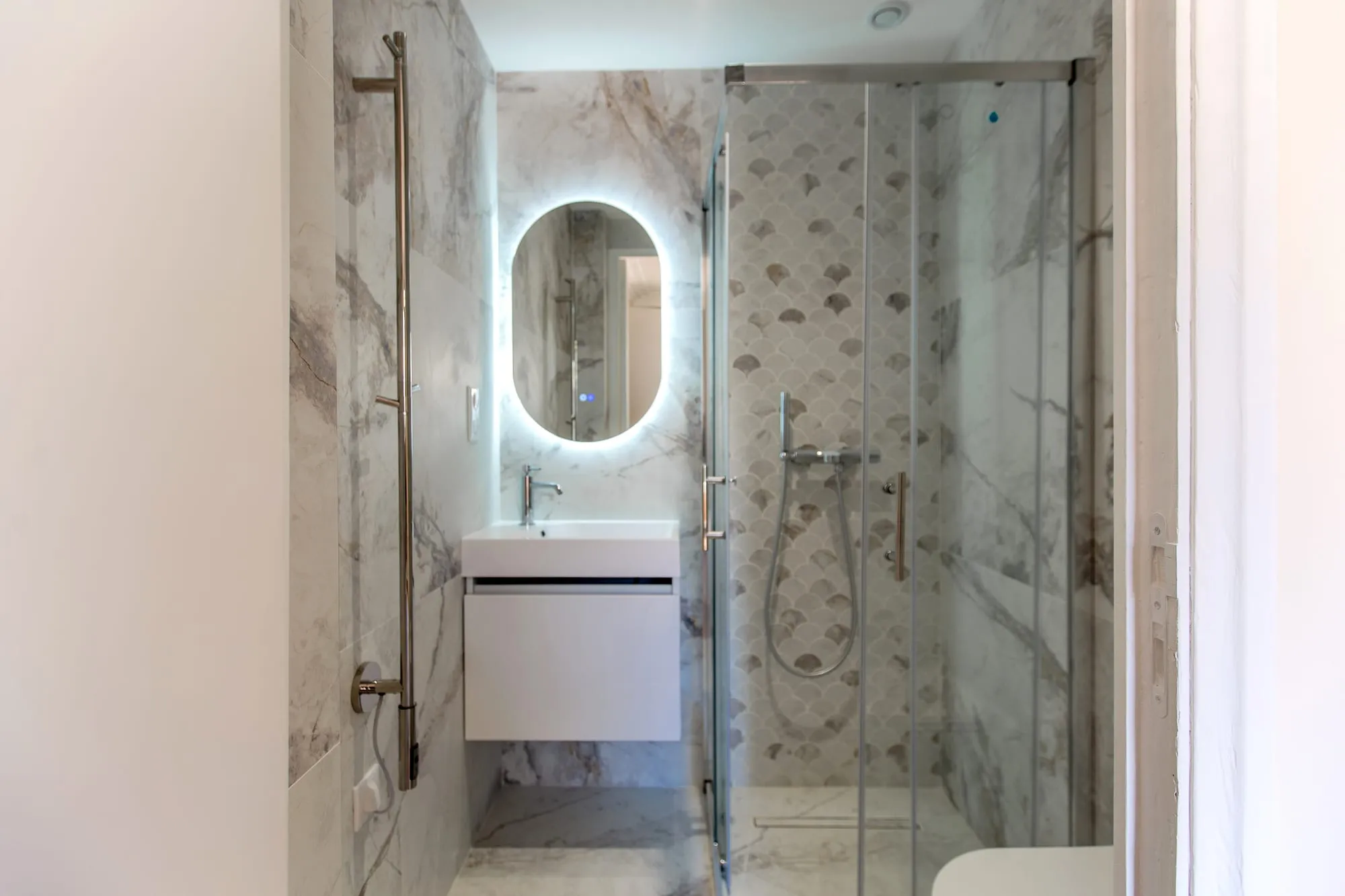 Salle d'eau en marbre avec douche vitrée et vasque suspendue